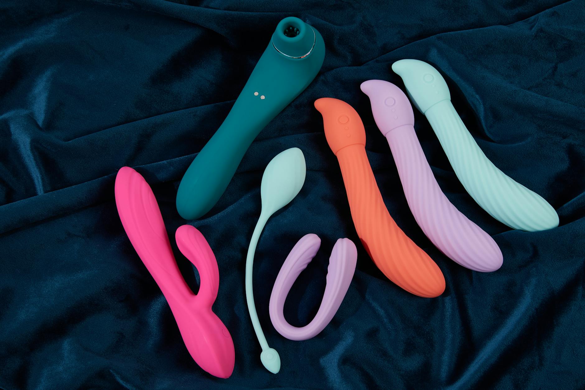 Vibromasseur clitoridien bleu en silicone tenu à la main sur fond violet