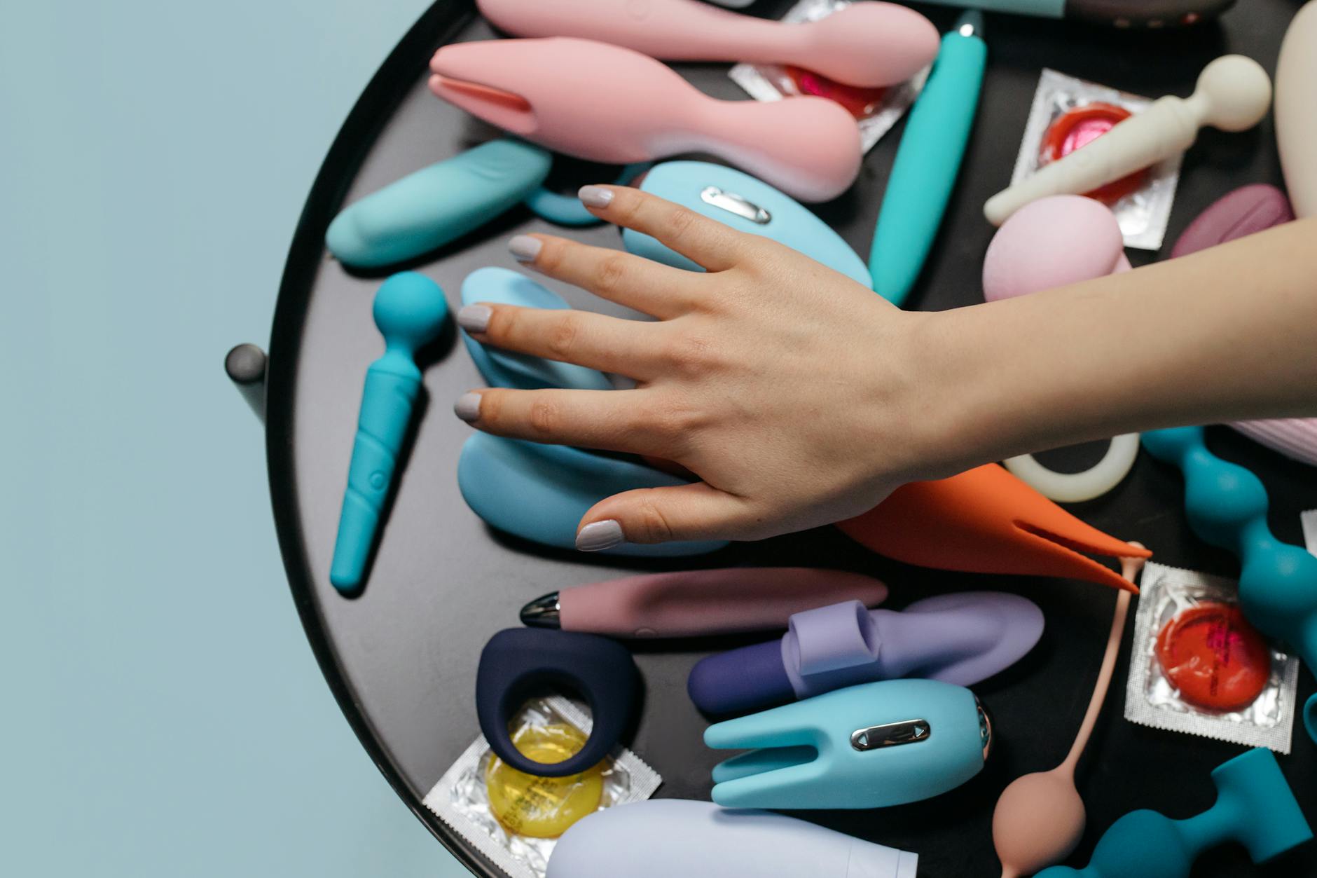 A vibrant collection of various sex toys on a black tray, featuring diverse shapes and colors.