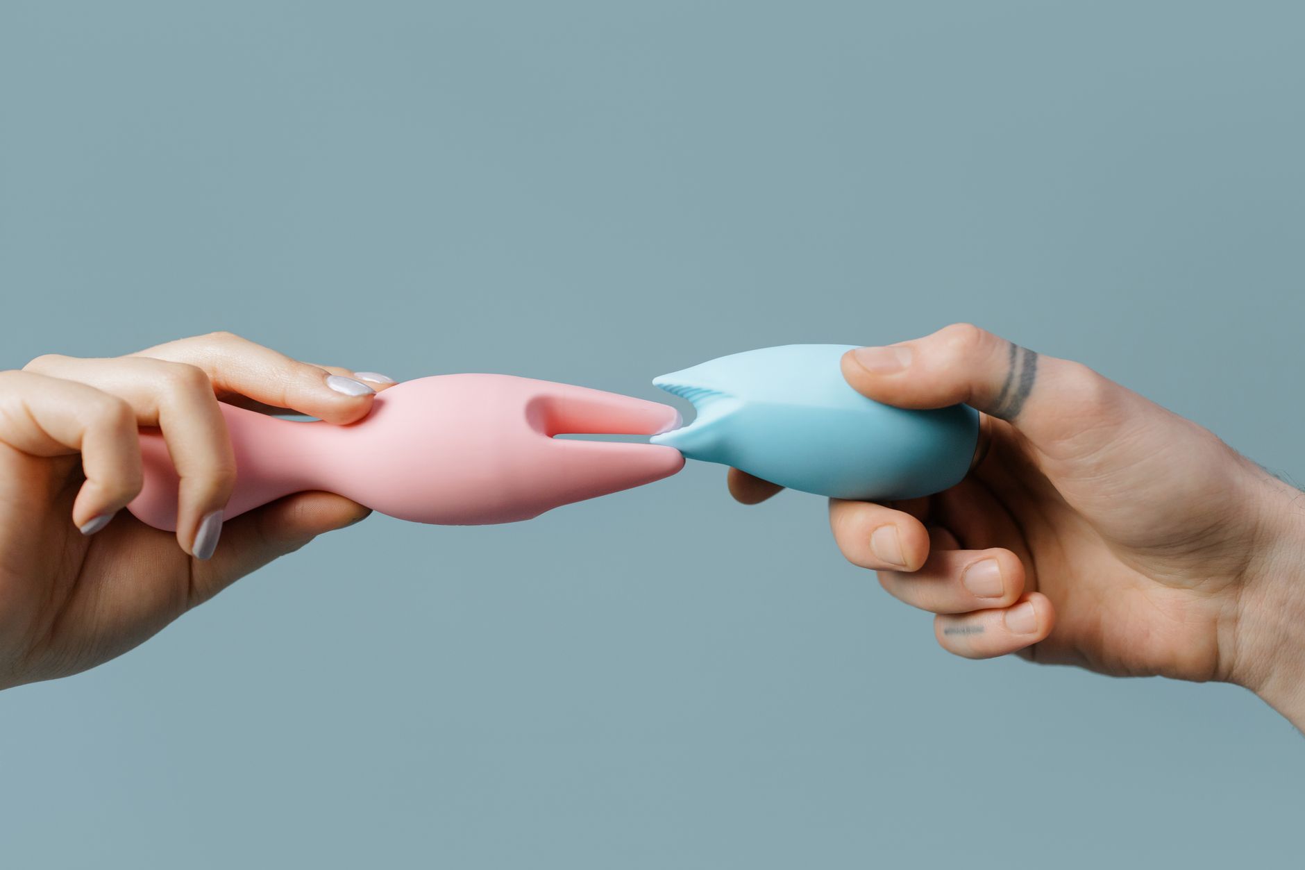 Close-up of hands holding pastel-colored silicone vibrators and personal massagers.