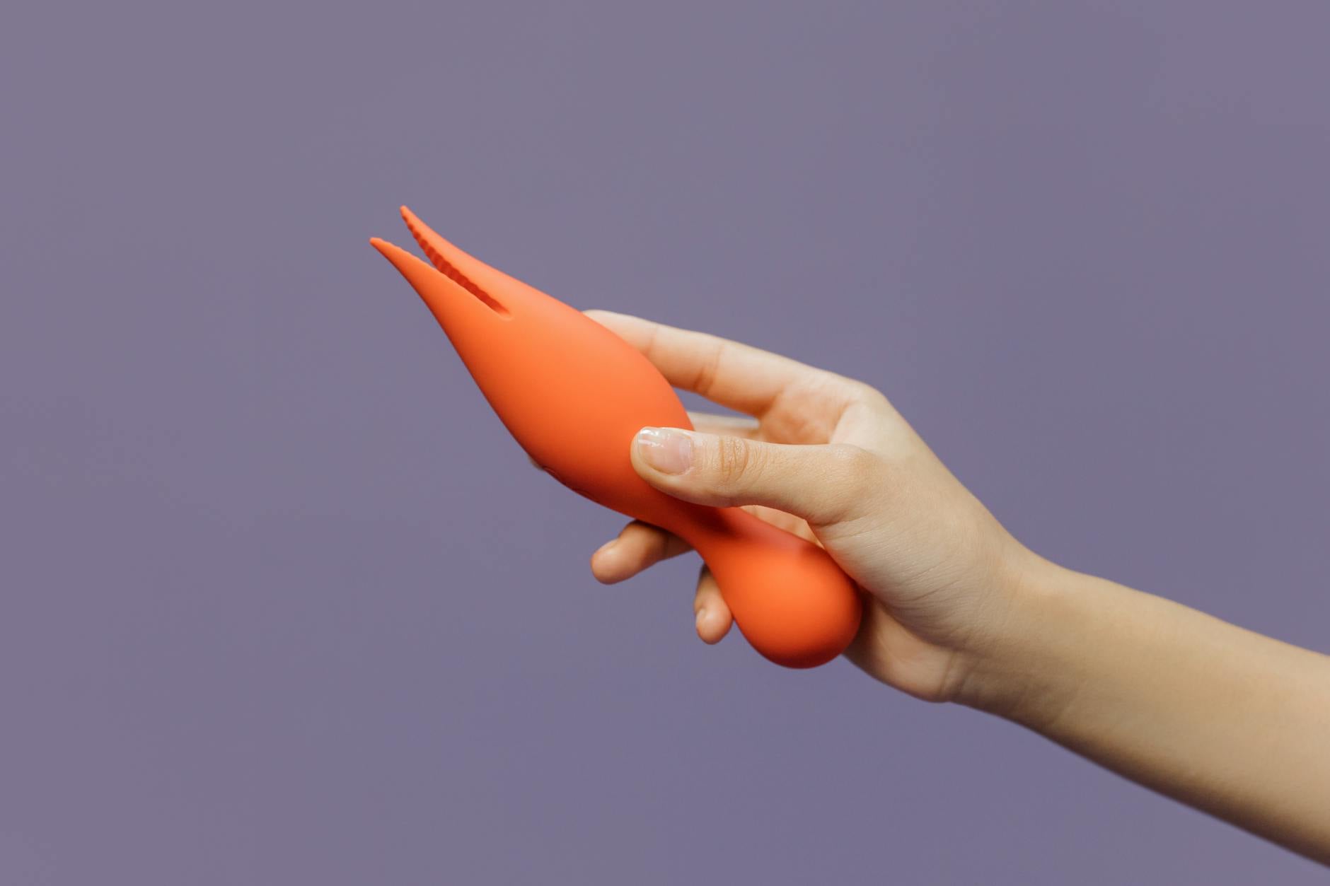 Hand holding a yellow lemon vibrator against a minimalist purple background