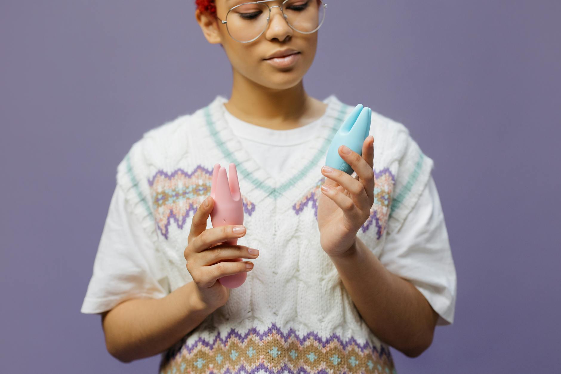 Woman holding a blue silicone clitoral vibrator in a thoughtful moment, representing solo self-discovery and personal pleasure exploration.