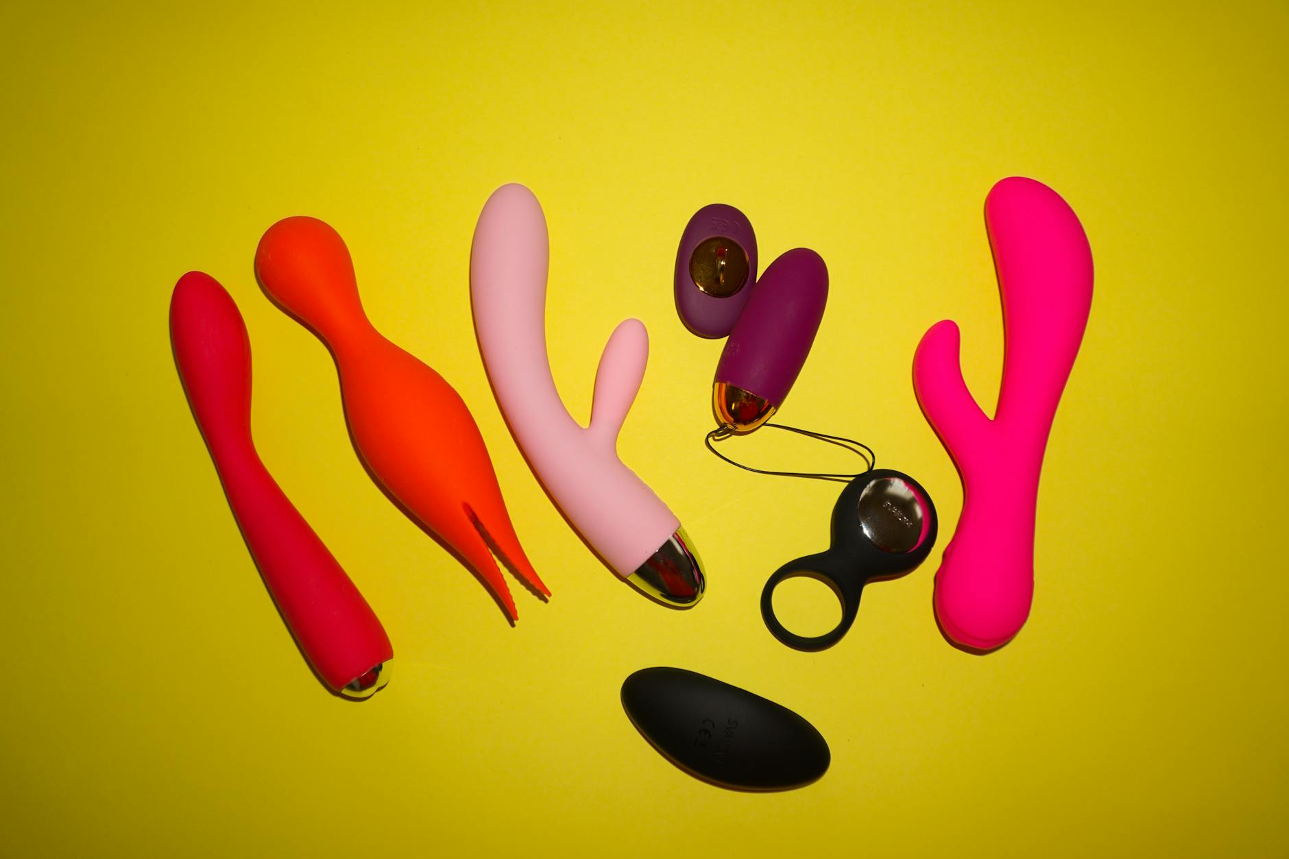 Colorful clitoral vibrators and sexual wellness toys arranged on a bright yellow background